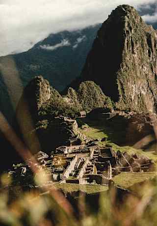 High-angle view of the green citadel of Machu Picchu in a mountaintop cradle guarded by Huayna Picchu and Huchuy Picchu.
