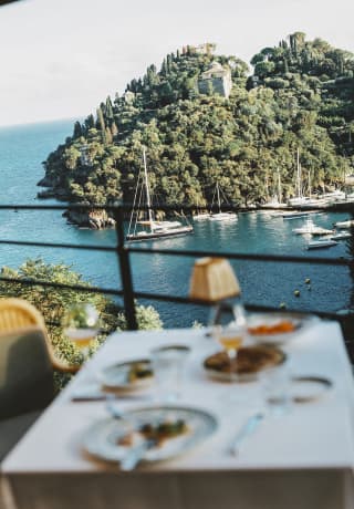 Soft-focus image of a dining table at Splendido Grill with views over the crystal Ligurian waters, where boats line the bay.
