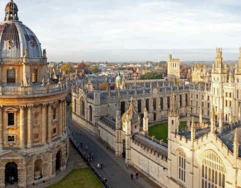 View from above of Oxford's Radcliffe Camera Library and All Souls College, as the yellow-tinted stone glows in evening sun.