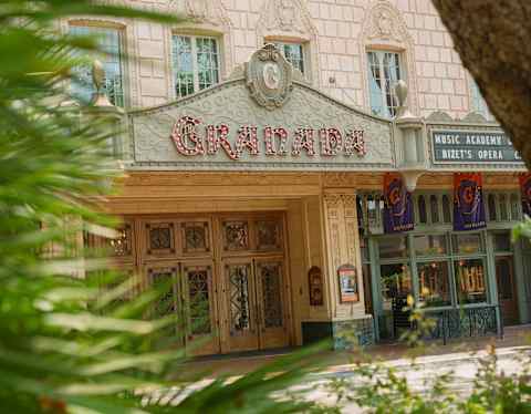 The Granada theatre, with a lightbulb sign, carries nineteen-twenties glamour and Spanish influence, viewed through palms.