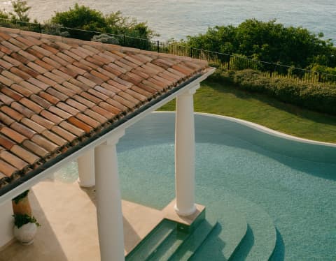 Aerial view of the terracotta-roofed veranda with column supports extending into the pool, with access steps on both sides.