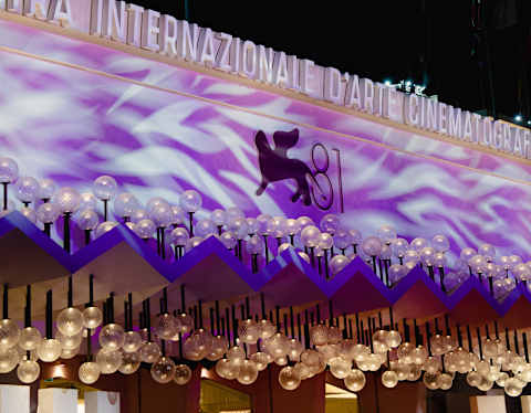 A purple cinema awning, glowing with white ripples and dripping with globe lights, advertises the eighty-first film festival.