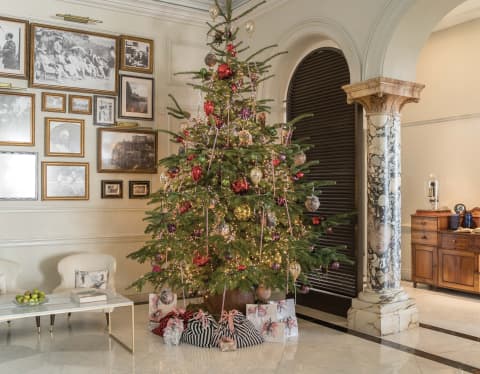 A tall Christmas tree, with baubles and tinsel in red and gold, creates a true festive splash in the white marble lobby.