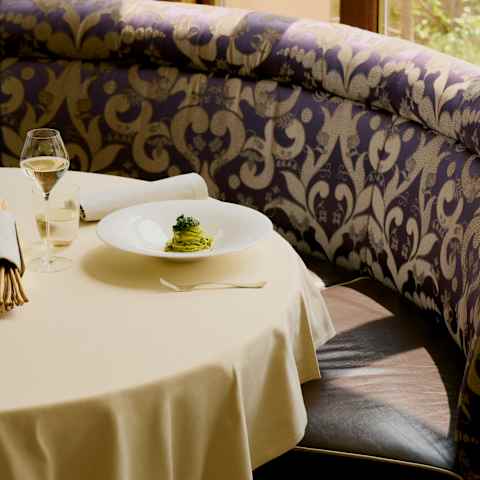 A dish of tagliolini pasta in a vibrant green nettle, lemon and cheese sauce, served with white wine, seen on a table at Oro.