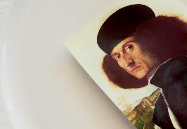 A card with the self-portrait by Venetian Renaissance painter Vittore Carpaccio rests on a plate, seen in close-up at Oro.