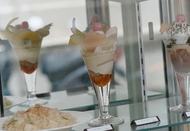 Glasses of cherry-topped sundaes and trifles on display in a shop window in Tokyo, photographed by Cecy Young.