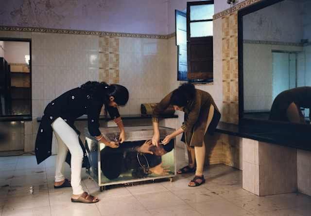 Two magicians fix locks to a water tank containing a submerged boy in Tara L. C. Sood's The Great Mandrake Magic Convention.