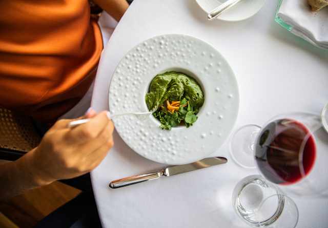 Looking down on a bowl of whipped seaweed-green puree with leaves and carrot, served with red wine at William Restaurant.