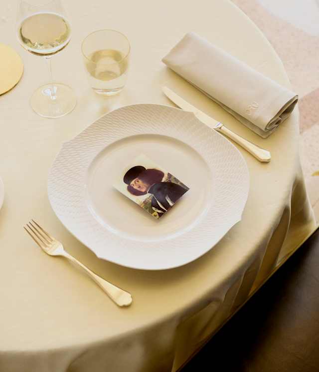 A card with a self-portrait by the Italian painter Vittore Carpaccio rests in the centre of a plate, with cutlery either side.