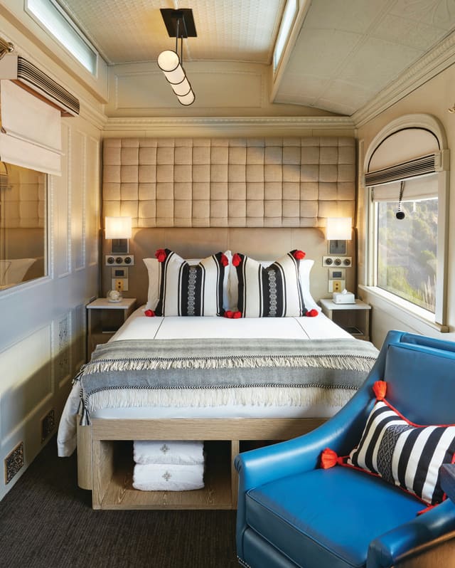 A comfortable double cabin with Peruvian-style soft furnishings, neat storage, and a blue leather armchair next to a window.