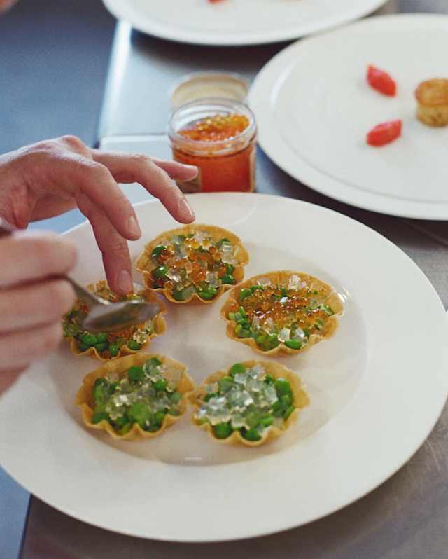 Chef Dominique Crenn fills tartlets with bright peas and juicy roe for an on-board dining experience, seen in close-up.