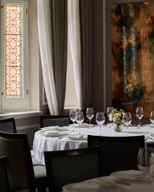 The Lillie room window spills light onto a dining table, illuminating the white tablecloth and crystal clear wineglasses.