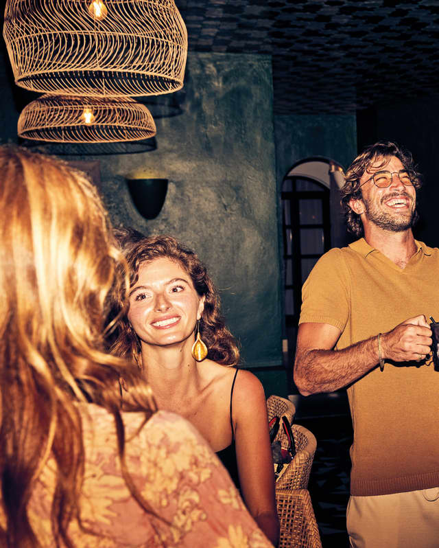 Stylish guests laughing and talking in a bar at night