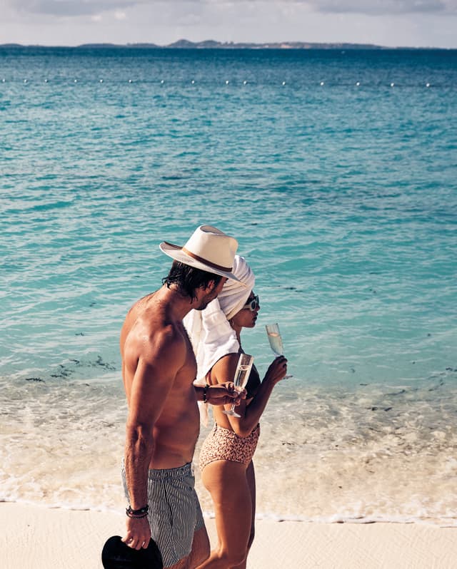 A couple in swimsuits taking a stroll along the tranquil shoreline of Maundays Bay