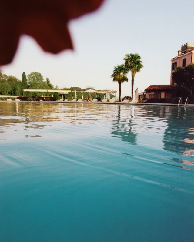 An Olympic sized outdoor pool stretches into the distance. On the far edge are two palms and the Hotel Cipriani’s pink walls