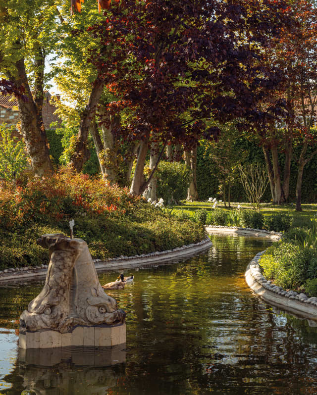 A stone, double-headed animal water feature adds romance and intrigue to the pond in Hotel Cipriani's Casanova Gardens.