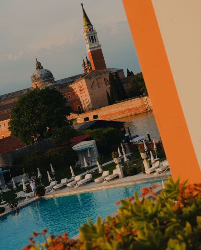 Peering out through a balcony wall is a view of the Olympic sized outdoor pool, the canal and Abbey of San Giorgio Maggiore