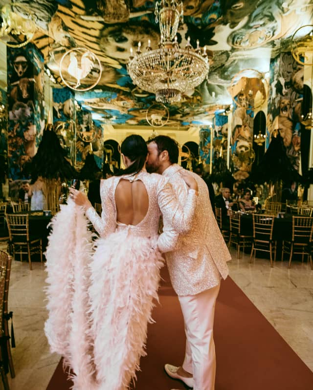Shot from behind of a newly married couple in sharing a kiss in a glamorous room