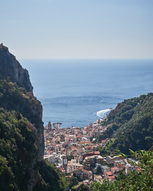 View from the hillside village of Pontone of the red-roofed town of Amalfi below, tumbling down the green slopes to the sea.