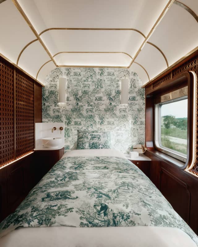 View into a panelled Dior Spa room with a teal and white Toile De Jouy feature wall and treatment bed with matching covers.