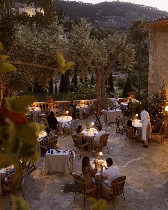Seen from above, table lamps glow like fireflies during a magical evening on the terrace of El Olivo, circled by gardens.