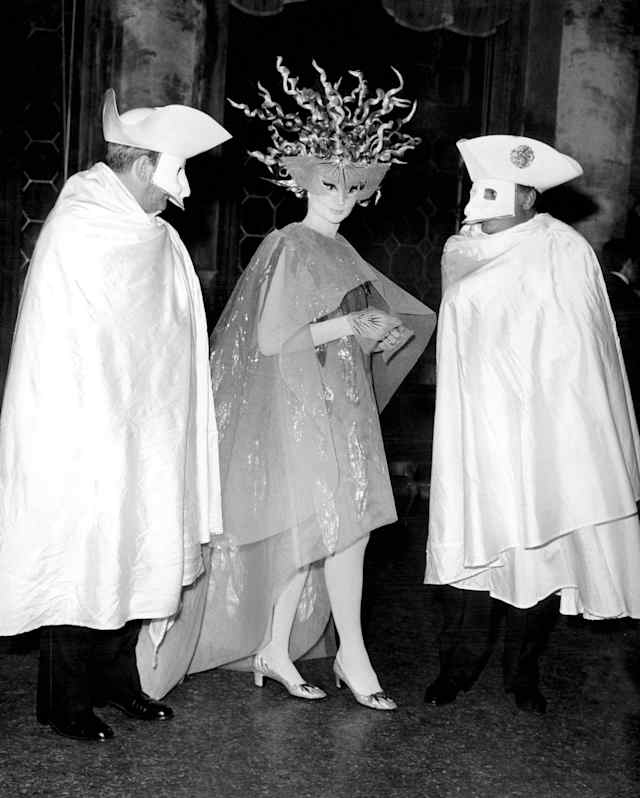 Visconti chats with Viscountess Jacqueline of Ribes and actor Franco Rosi, photographed at a costume ball in monochrome.
