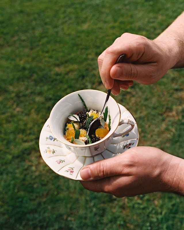 A diner digs a spoon into a dainty teacup of Oro's Lagoon dish, with mussels, caviar, blue crab, bottarga and sea fennel.