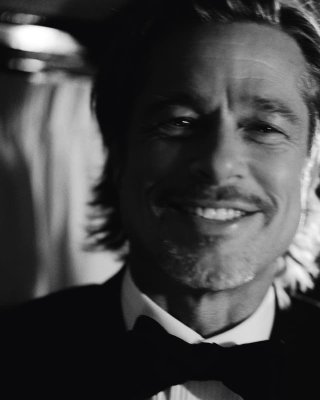 A soft-focus, black and white image of actor, Brad Pitt, smiling in a black bow-tie, white shirt and tuxedo jacket.