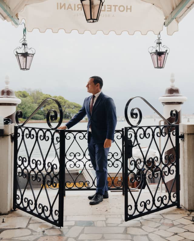 Andrea Zennaro, doorman at Hotel Cipriani, prepares to greet guests at the filigree gates under the hotel's entrance awning.