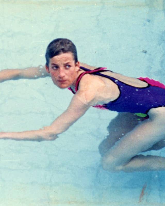 Brazilian model, Alessandra Ambrósio swims away from the side of the pool in a red and pink one-piece swimming costume.