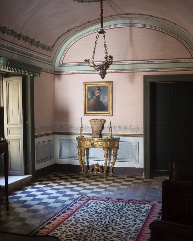 Room detail from the eclectically restored Palazzo Castelluccio, with gilded table, checked tiling and leopard-print carpet.