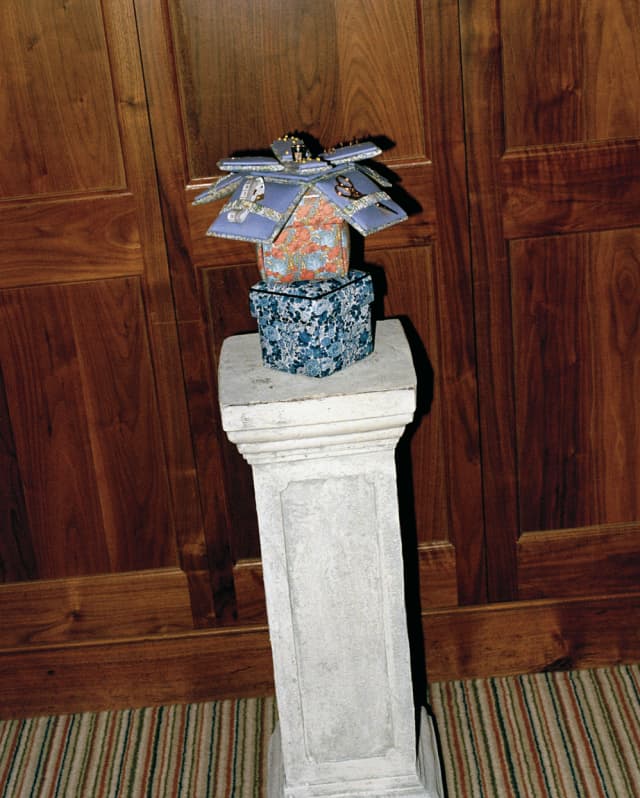 Created by Doris Boyle, a stack of three sewing boxes, the top one opened outwards like a flower, rest on a stone plinth.
