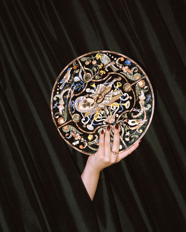 A hand holds an ornate plate decorated with birds and a violin, to commemorate Vanessa-Mae's garden concerts at Le Manoir.