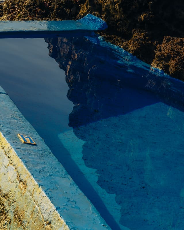 Reflections of rock float in the water of the blue-painted pool in a detail of the sea platform below Reid's Palace.