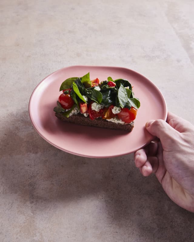 Traditional chapla bread topped with sachatomates, lemon balm cream and fresh spinach, served on a rose-pink plate at Mauka.