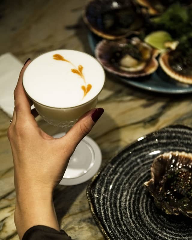 Close up shot of a guest's hand holding a cocktail at the Belo Bar
