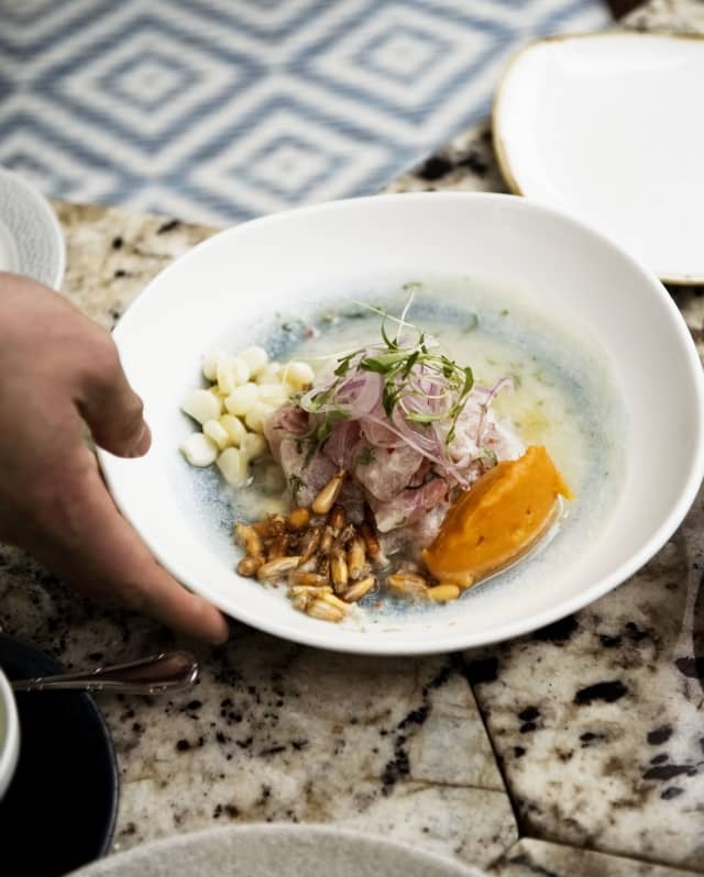 A waiter serves a white dish of fine cuisine at the Restaurant Tragaluz in Hotel Miraflores Park