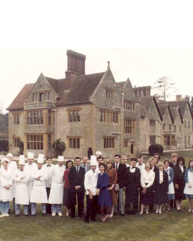 An old photograph of the Le Manoir Aux Qaut'Saisons team, with staff and chefs in toques, taken on the lawns of the property.