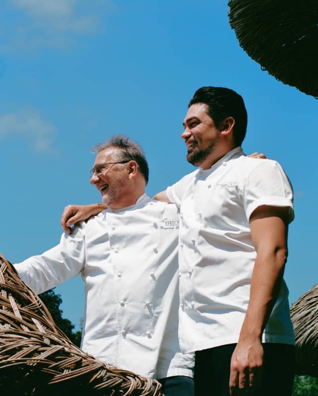 Low-angle shot of Chef Patron Raymond Blanc and Executive Chef Luke Selby smiling, with arms on each other's shoulders.