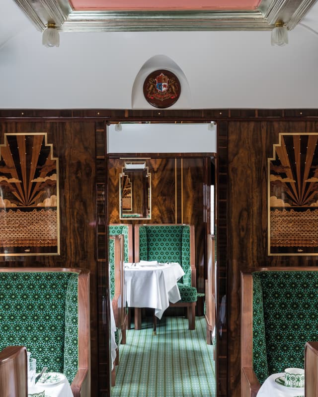 Stunning marquetry depicts art deco sunsets on the horizon of an expansive sea set into the polished wood panel wall