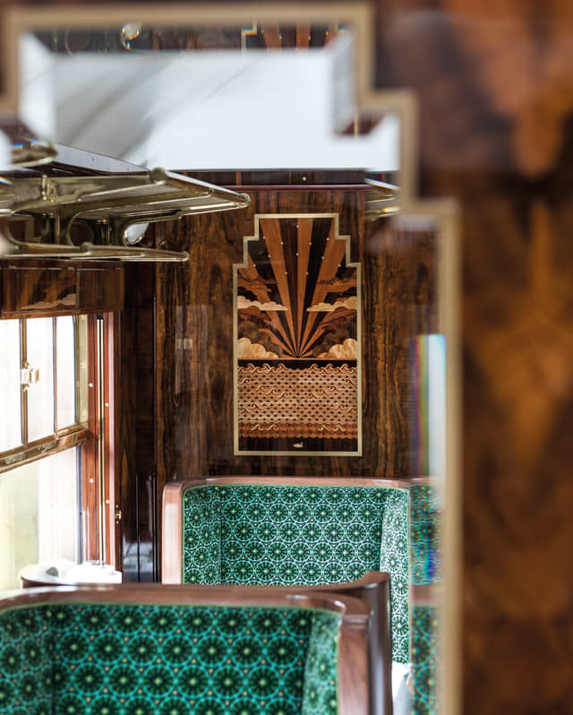 Narrow triangles of alternate dark and pale wood marquetry fan out in an art deco sunset, framed by symmetrical clouds
