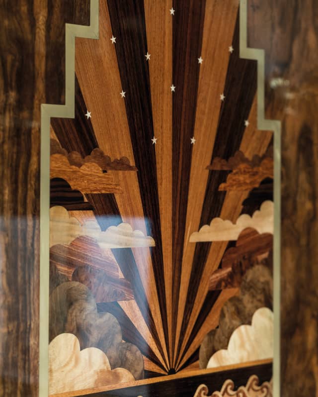 Tiny white stars pepper an alternating pale and dark sunburst of art deco marquetry. Waves toss below an horizon line