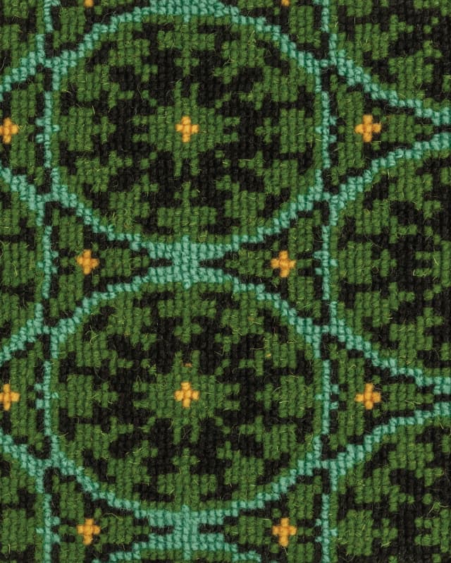 The upholstery features a tiny yellow cross at the centre of aquamarine circle, on a green background filled with black zigzags