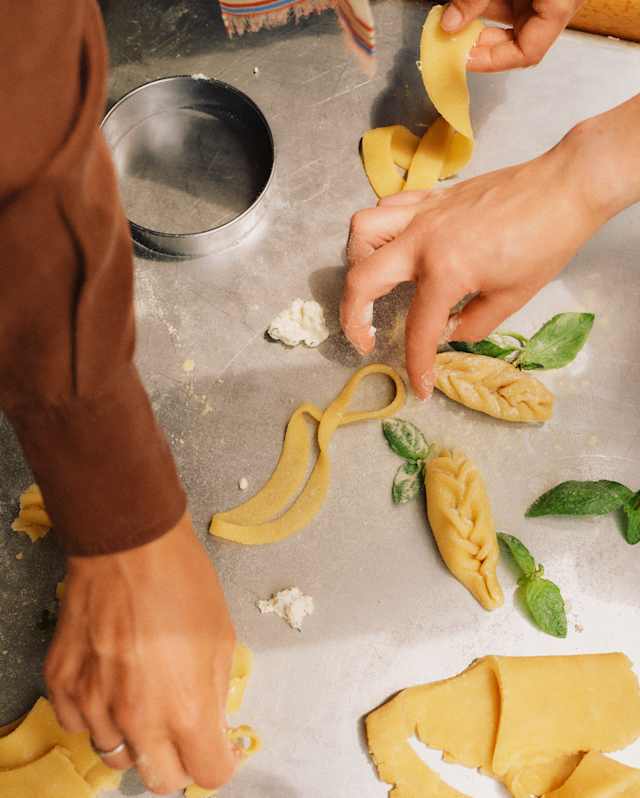 Guests create culurgiones, stuffed pasta with an ear-of-wheat shape, in a cooking class, seen from above, close-up.