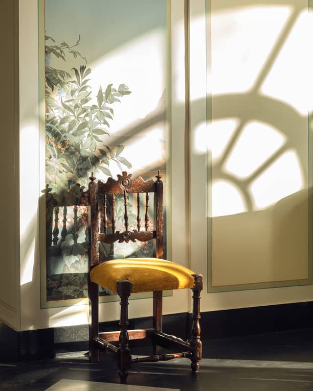 Antique chair with a mustard yellow velvet seat in a marble-floored hotel lobby