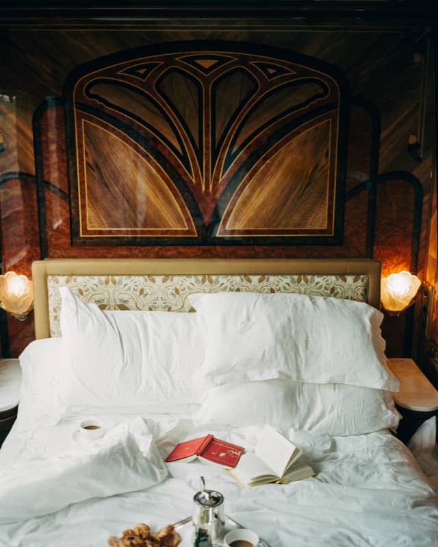 In La Foret, open books and a breakfast tray rest on the white linen of an unmade bed, nestled in the rich wooden surrounds.