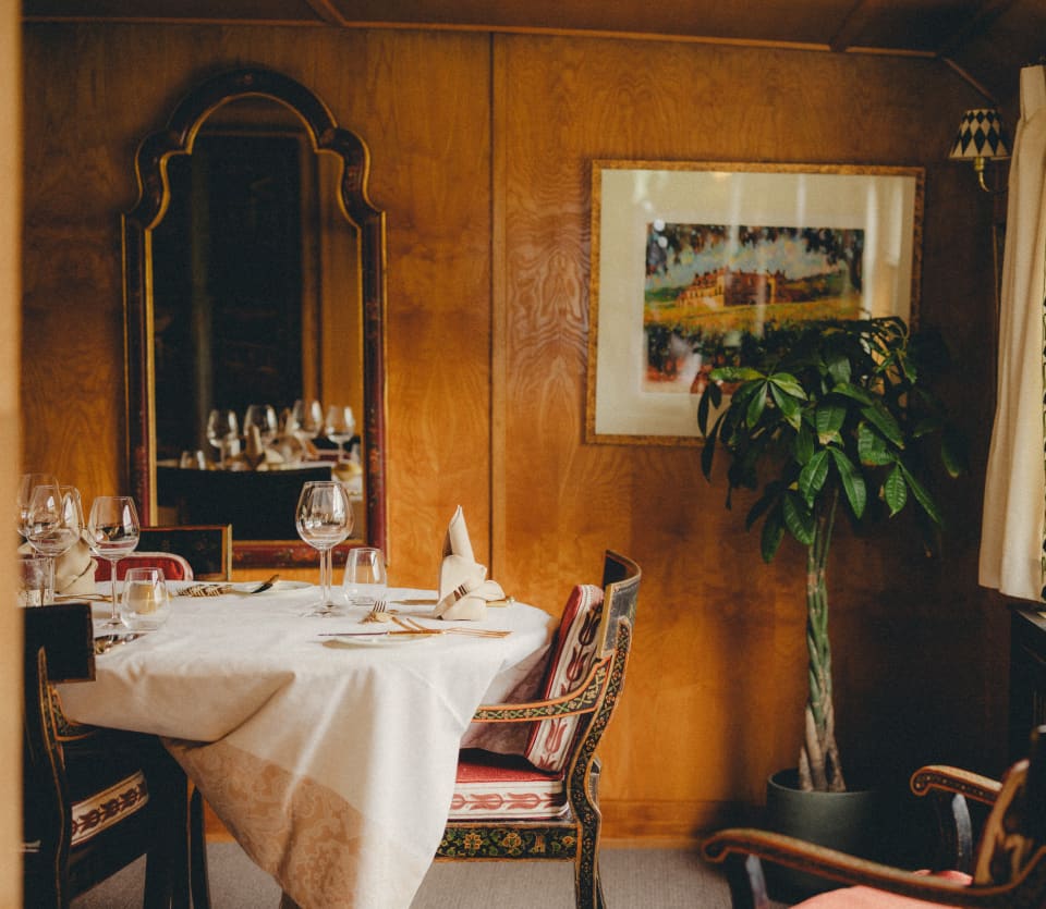 Dining room detail, with light from the window sparkling on wineglasses and revealing the shine of the rich walnut interior.