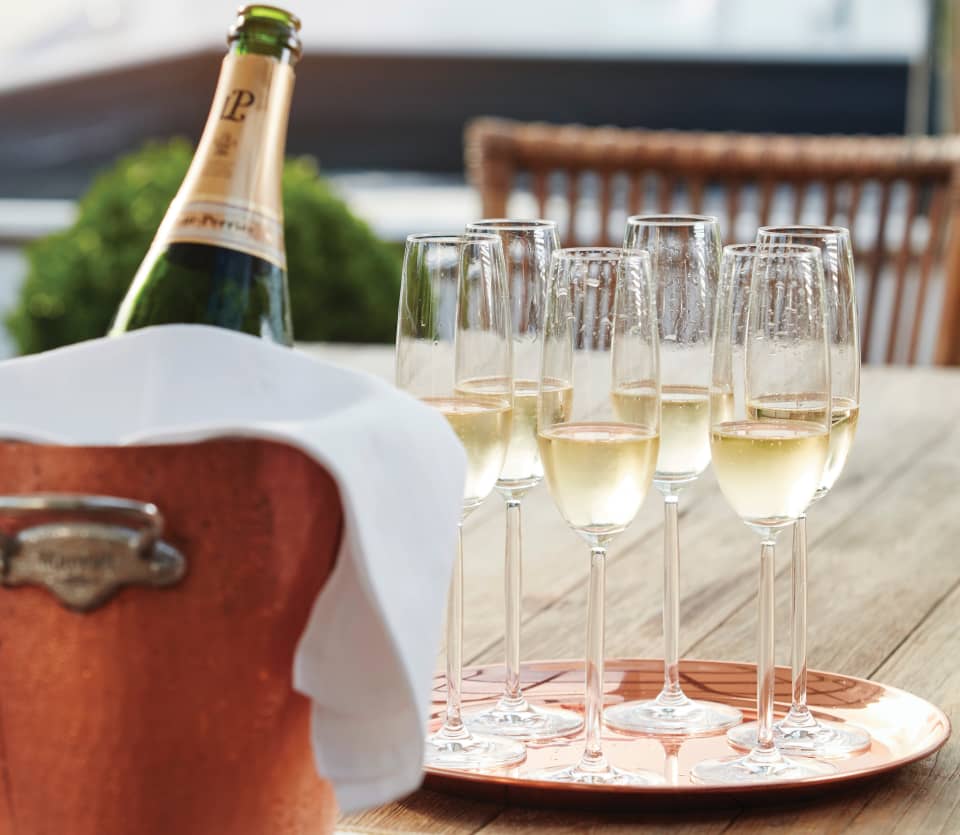 Bottle of Laurent Perrier champagne in a cooler beside filled flute glasses