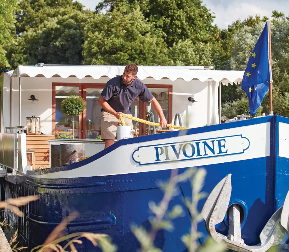 Deckhand on a luxury river barge preparing to throw a rope on shore