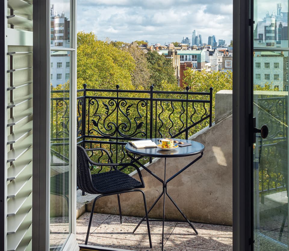 Open French doors give access to the penthouse suite terrace and a bistro table laden with an open book and a cup of tea